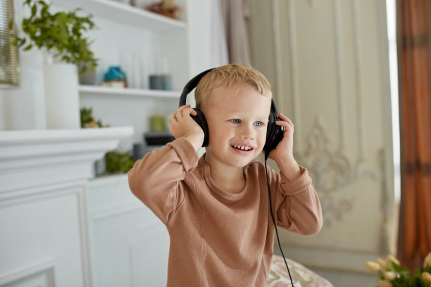 男孩在家里玩得很开心，还在沙发上跳。孩子们一边跳舞，一边戴着耳机听音乐图片下载