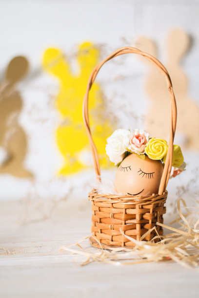 带着笑脸的复活节彩蛋。有趣的复活节彩蛋装饰黄玫瑰花环和纸兔子。复活节彩蛋正在睡觉。图片下载