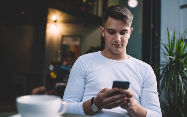 专注的商人在舒适的自助餐厅喝咖啡休息时使用智能手机图片下载