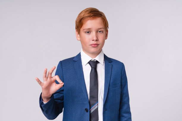 严肃的红发小男孩在灰色背景下显示正常迹象图片下载
