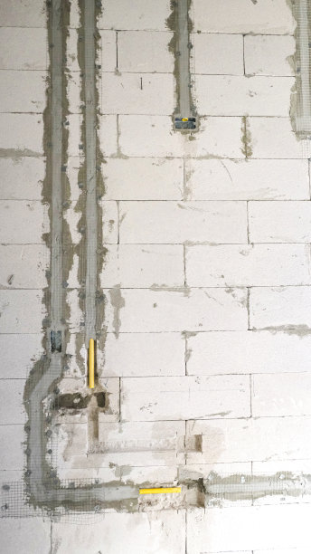 黄色电灯灯管安装在混凝土白墙上，用于建筑厕所。维修管路的固定。图片下载