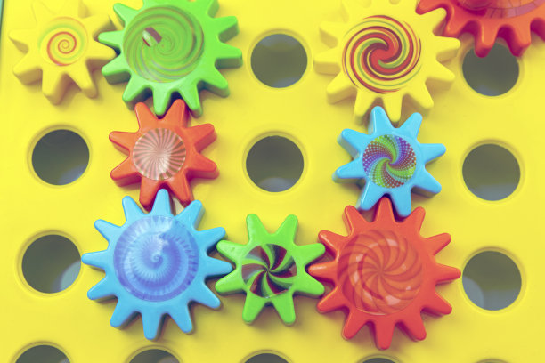 团队合作和团结的概念相关的彩色塑料玩具齿轮，每个齿轮是一个不同的颜色上的蓝色背景与复制空间图片下载