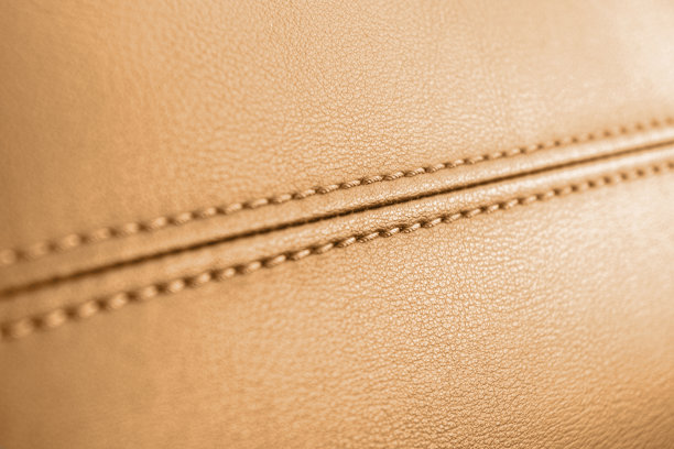 现代豪华轿车棕色皮革内饰。部分穿孔皮革汽车座椅细节。橙色穿孔皮革纹理背景。纹理，人造皮革与缝线。真皮仪表板图片下载