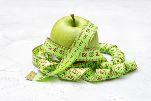 新鲜的青苹果，用卷尺放在水泥桌上图片下载