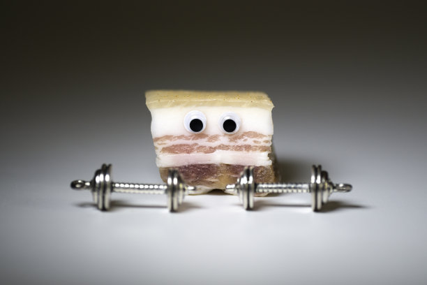 可爱的猪油角色看着沉重的哑铃在一个中性的背景。图片下载