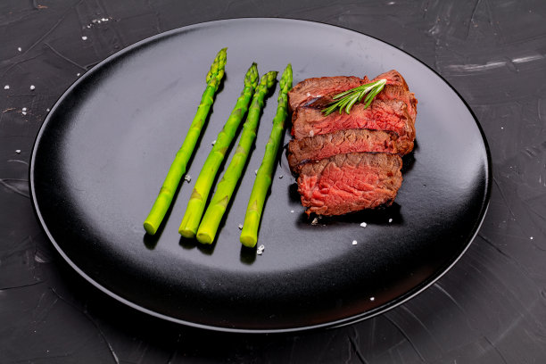 多汁的半熟牛排放在陶瓷盘子里，配上香草、香料和盐。图片下载