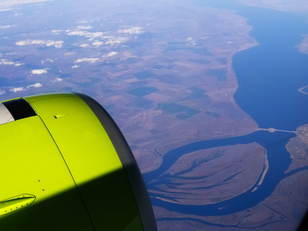 从飞机窗口看到的土地、河流和涡轮机。旅行的概念。手机照片。图片下载