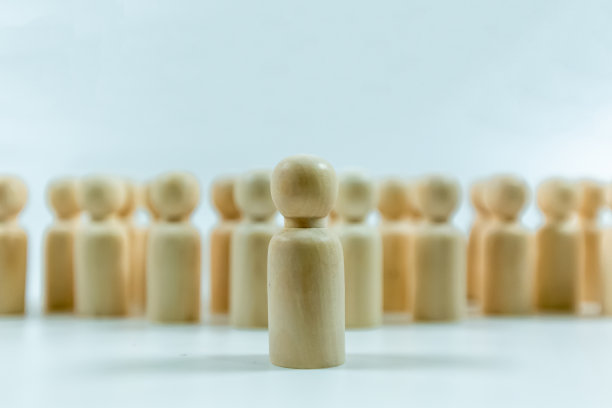 从人群中脱颖而出，以白色背景上的木制小雕像为领导理念图片下载