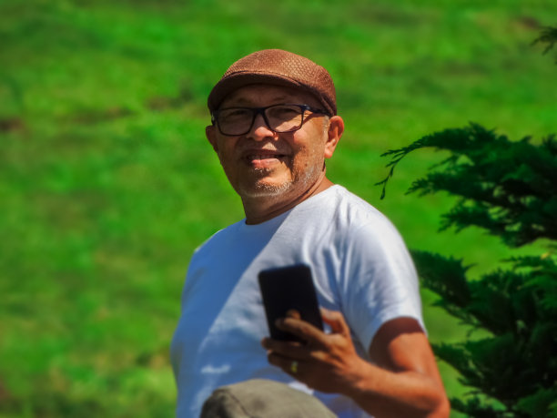 一个健康快乐的老人在绿色的自然背景下的高分辨率照片图片下载