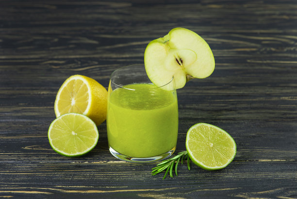 新鲜的绿色玻璃玻璃片柠檬，苹果和酸橙在木制的深色背景。图片下载