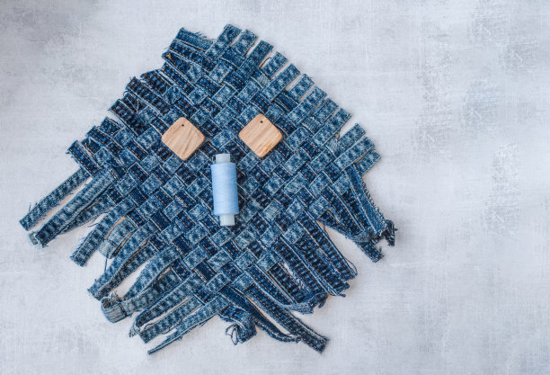 旧牛仔裤上的滑稽脸缎带，线轴和木制纽扣。物品再利用和自然资源保护的概念。图片下载