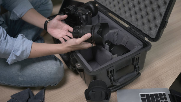 男子摄影师手把相机配件放在袋子里的剪影。图片下载