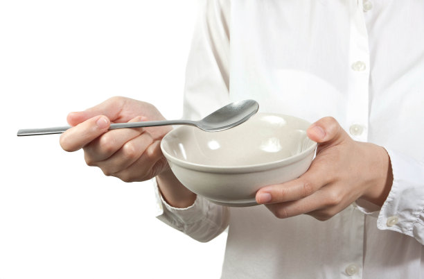 双手握住碗和勺子在白色的背景图片下载