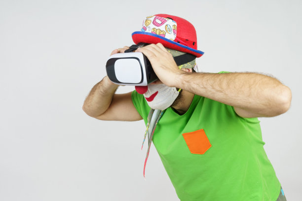 小丑正在玩，他的头上戴着虚拟眼镜，看起来像通过双筒望远镜。孤立在白色图片下载