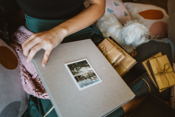 亚洲年轻女子坐在她新家的地板上，打开她的结婚周年礼物。图片下载
