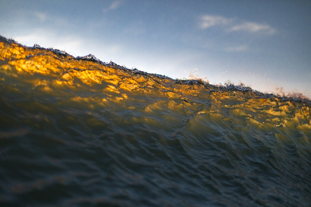 金色的波浪打破在温暖的光在日落在海洋的近距离图片下载