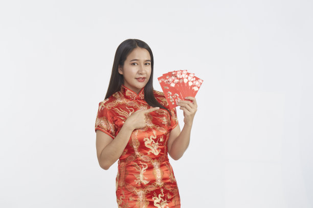 年轻的亚洲女子在传统的红色旗袍拿着幸运与红包信在浅灰色孤立的工作室背景图片下载