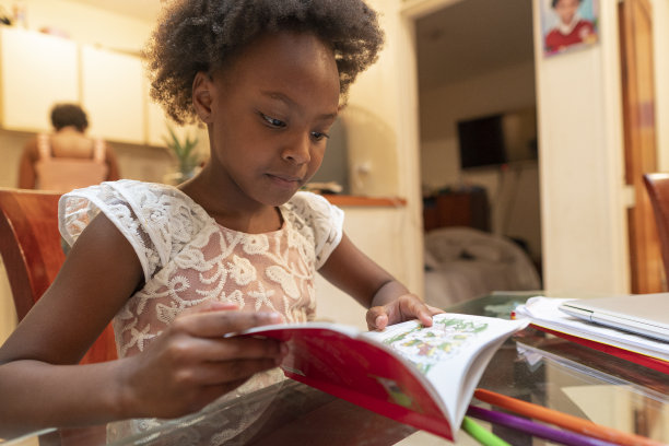 漂亮的非洲裔女孩写完作业后在餐厅看书图片下载