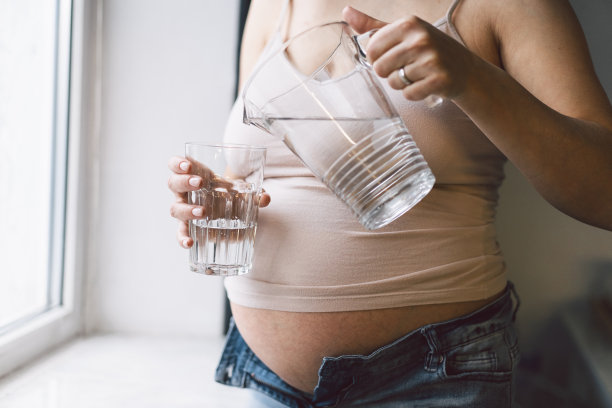 孕妇在窗边喝水。图片下载