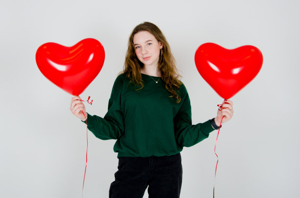 白色背景下拿着气球的女孩。庆祝生日、情人节、妇女节的概念图片下载