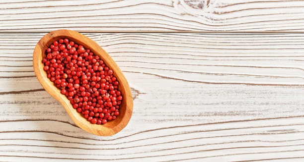 红色或粉色的胡椒放在小木碗里，放在白板桌上，上面有特写照片，右边有文字空间图片下载