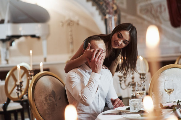 惊讶的是,猜猜谁。美丽的夫妇在晚上的豪华餐厅享用浪漫的晚餐图片下载