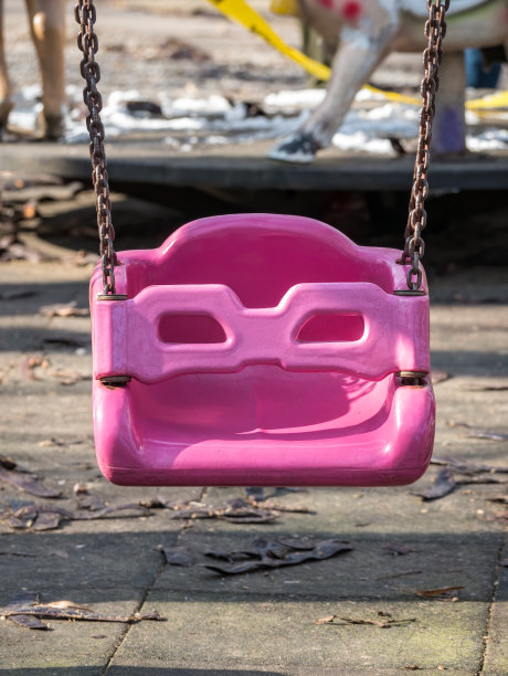 近距离拍摄一个粉红色的塑料儿童在公园荡秋千。图片下载