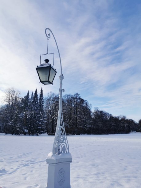 在圣彼得堡埃拉金岛的一个白雪覆盖的公园里，开放的美丽的路灯映衬着亭台楼阁和蓝天白云图片下载