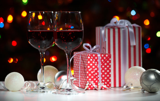 酒杯，圣诞礼物和球在圣诞彩灯的背景图片下载