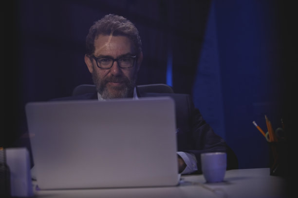 在办公桌前工作到很晚的成熟商人的正面视图图片下载