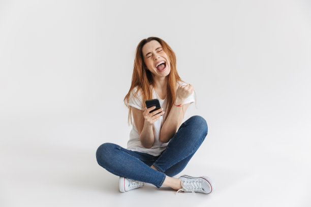 一个兴奋的年轻女孩使用手机的肖像图片下载