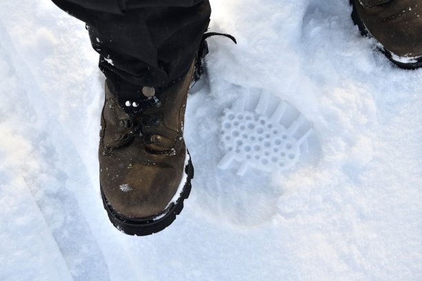 徒步旅行用的靴子和游客在雪地上留下的脚印图片下载