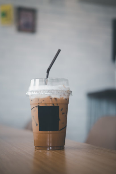 在咖啡馆的木桌上，用塑料杯装着奶油冰摩卡咖啡图片下载