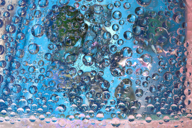 透明的水滴位于蓝色背景与蓝色和绿色的球。图片下载