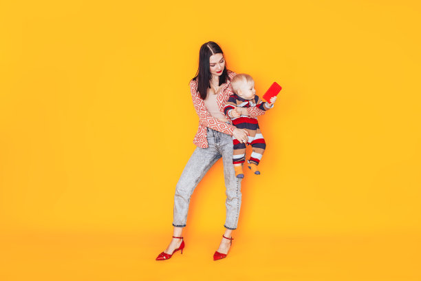 黄色背景下的妈妈带着孩子。一个没有父亲的幸福家庭。妈妈抱着一个小孩图片下载