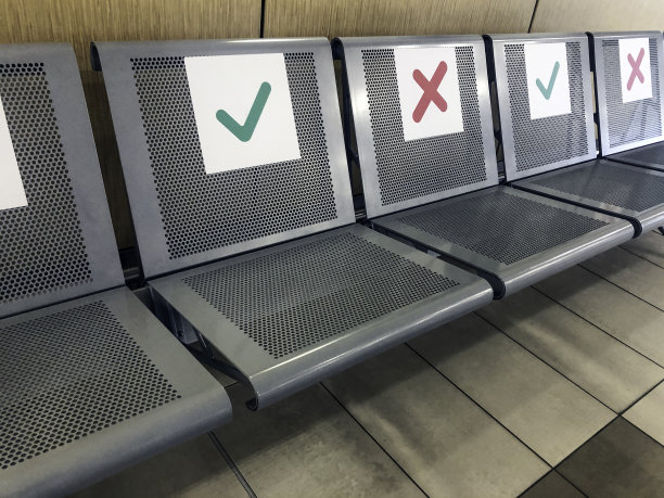 在新冠肺炎大流行期间，为了保持社会安全距离，应安排一排空椅子并注明可以坐的位置。社会距离的概念图片下载