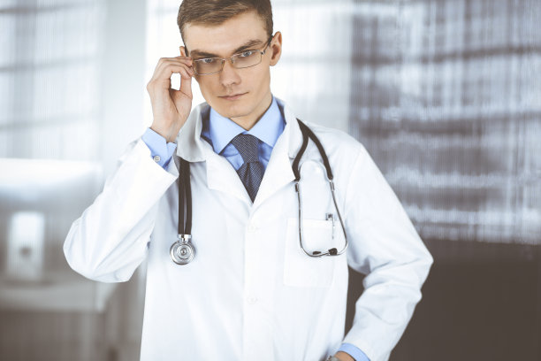 戴着眼镜和听诊器的男医生正站在医院的办公室里。诊所完善的医疗服务。医疗保健事业的美好未来图片下载