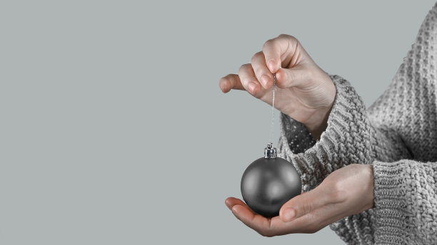 2021年的时尚灰色。女性手握圣诞球。色彩趋势的概念图片下载