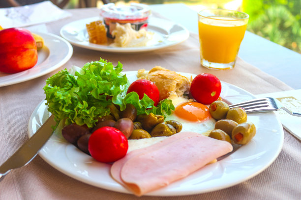 欧式早餐有煎蛋、橄榄、番茄、生菜、橙汁、水果和一片培根。早上好,健康的食物。有选择性的重点。图片下载