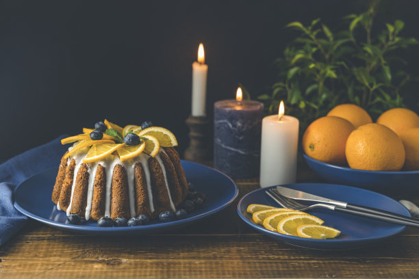 橙色蛋糕，以蓝莓为背景，水果，蜡烛，植物和餐具。图片下载