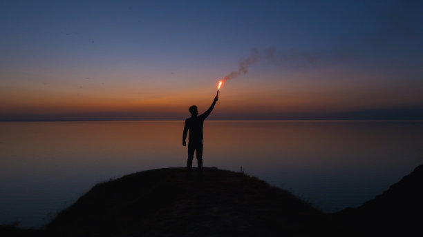 在靠近大海的山顶上，拿着一根火棒的人图片下载