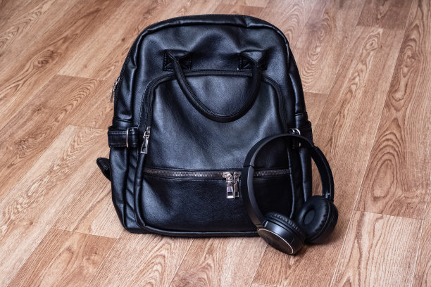 耳机和皮革背包放在木地板上图片下载