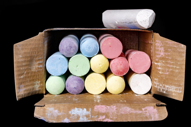 一盒彩色粉笔，用于街头绘画。学校用粉笔装在纸板箱里。黑暗的背景。图片下载