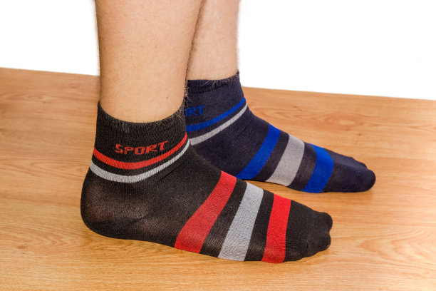 不同的袜子放在男人腿上的木地板上图片下载