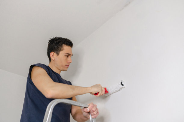 有人在梯子上用滚轴漆刷墙图片下载