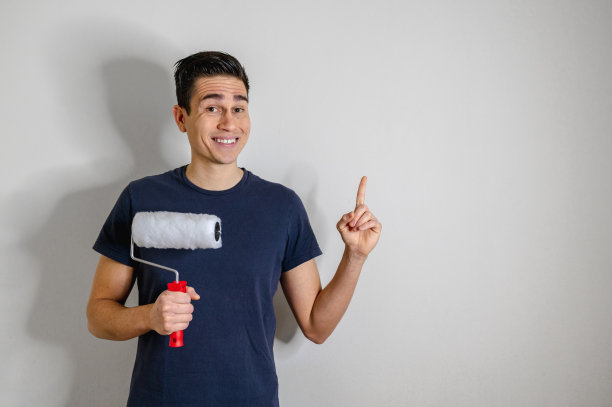 正面的男人肖像，拿着油漆滚筒，手指向上。图片下载