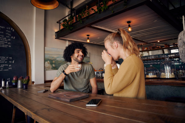 英俊的年轻人在现代咖啡馆和喝咖啡的女人聊天图片下载