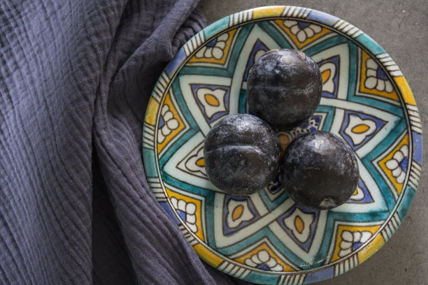 正宗的柠檬和李子盘子，蓝色陶瓷杯与红茶俯视图照片。蓝色静物画。图片下载