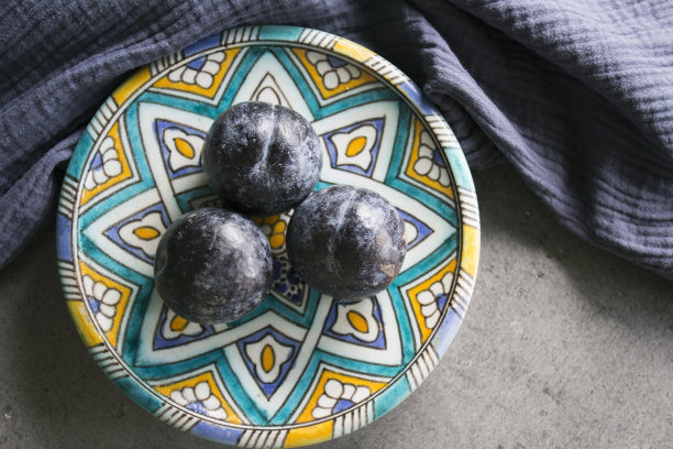 正宗的柠檬和李子盘子，蓝色陶瓷杯与红茶俯视图照片。蓝色静物画。图片下载