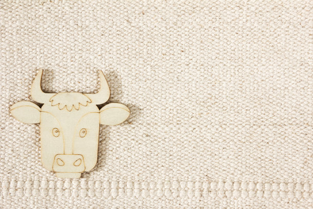 天然棉条纹无彩色纹理麻袋背景与一个木制雕像的奶牛。农业观，畜牧业图片下载